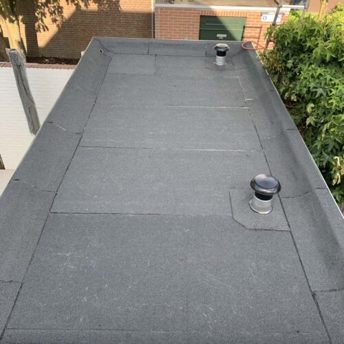Platte dakbedekking met waterdichte coating en ventilatieopeningen.